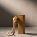 Scrubborstel naast de amberkleurige verpakkingsdoos met opschrift Scalp brush